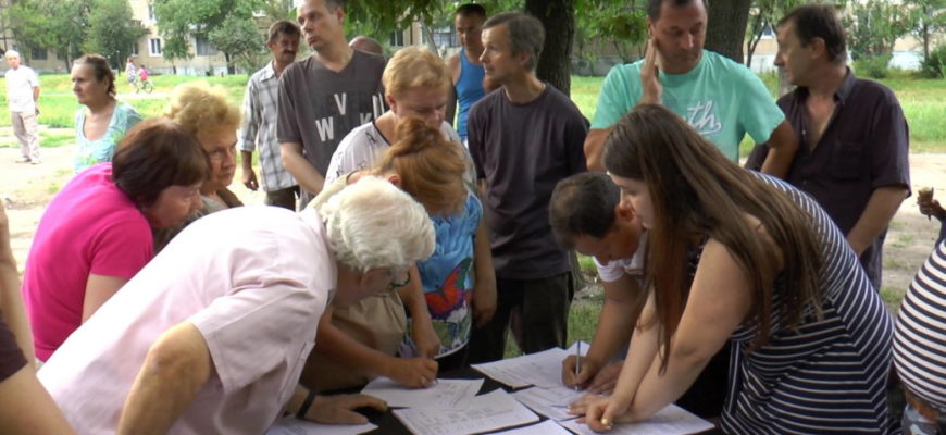 группа людей (жильцы и представители УК) обсуждают проблему в подъезде